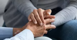 Person håller om annan persons händer.