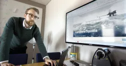 Viktor Stefansson lutar sig över sitt skrivbord och sin laptop.