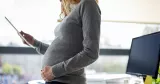 Kvinna med tidig gravidmage vid skrivbord.