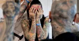 Kvinna med många tatueringar håller händerna för ansiktet.