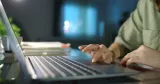 Närbild på kvinnas händer som skriver på en bärbar dator.