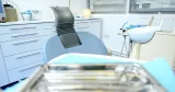 Tom tandläkarstol med tandvårdsinstrument på ett litet bord. 