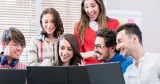 6 studenter samlade vid datorskärmar, ser glada ut.