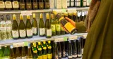 Ingen strejk på Systembolaget. På bilden en kund framför en hylla med vitvinsflaskor. 