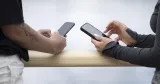 Två personer står med varsin mobiltelefon under en paus. Bilden illustrerar phubbing på jobbet och hur mobilanvändning kan påverka samtal mellan kollegor.