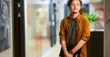 Christoffer Strokirk står på RFSU:s kontor med en dator i händerna.